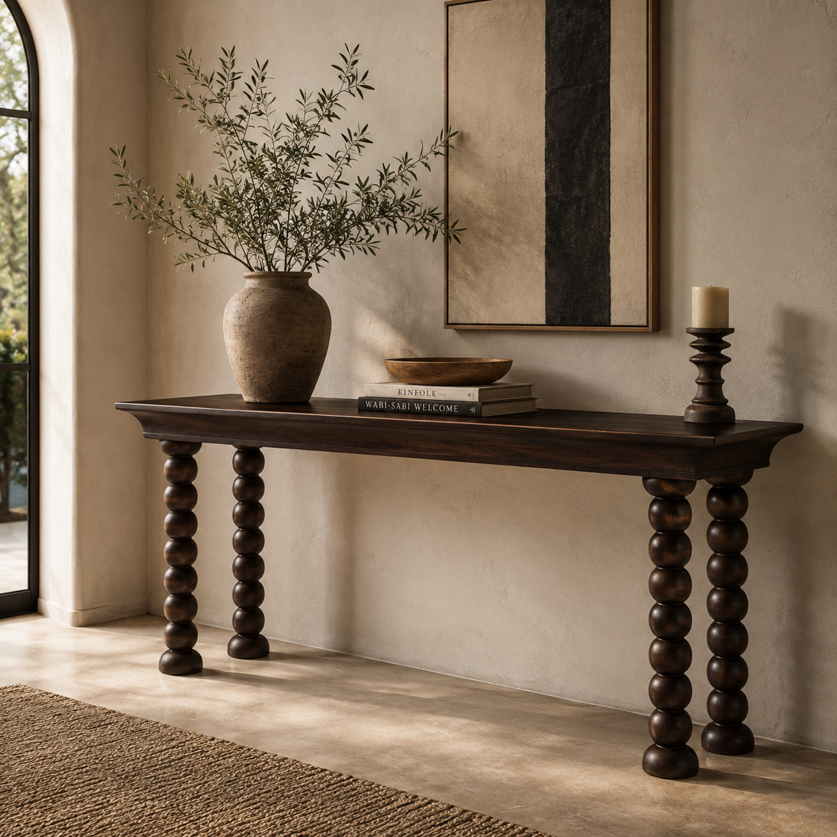 Monolith Console Table in dark walnut oak styled in a modern luxury entryway with ceramic vase, decorative books, artwork, and candle holder.